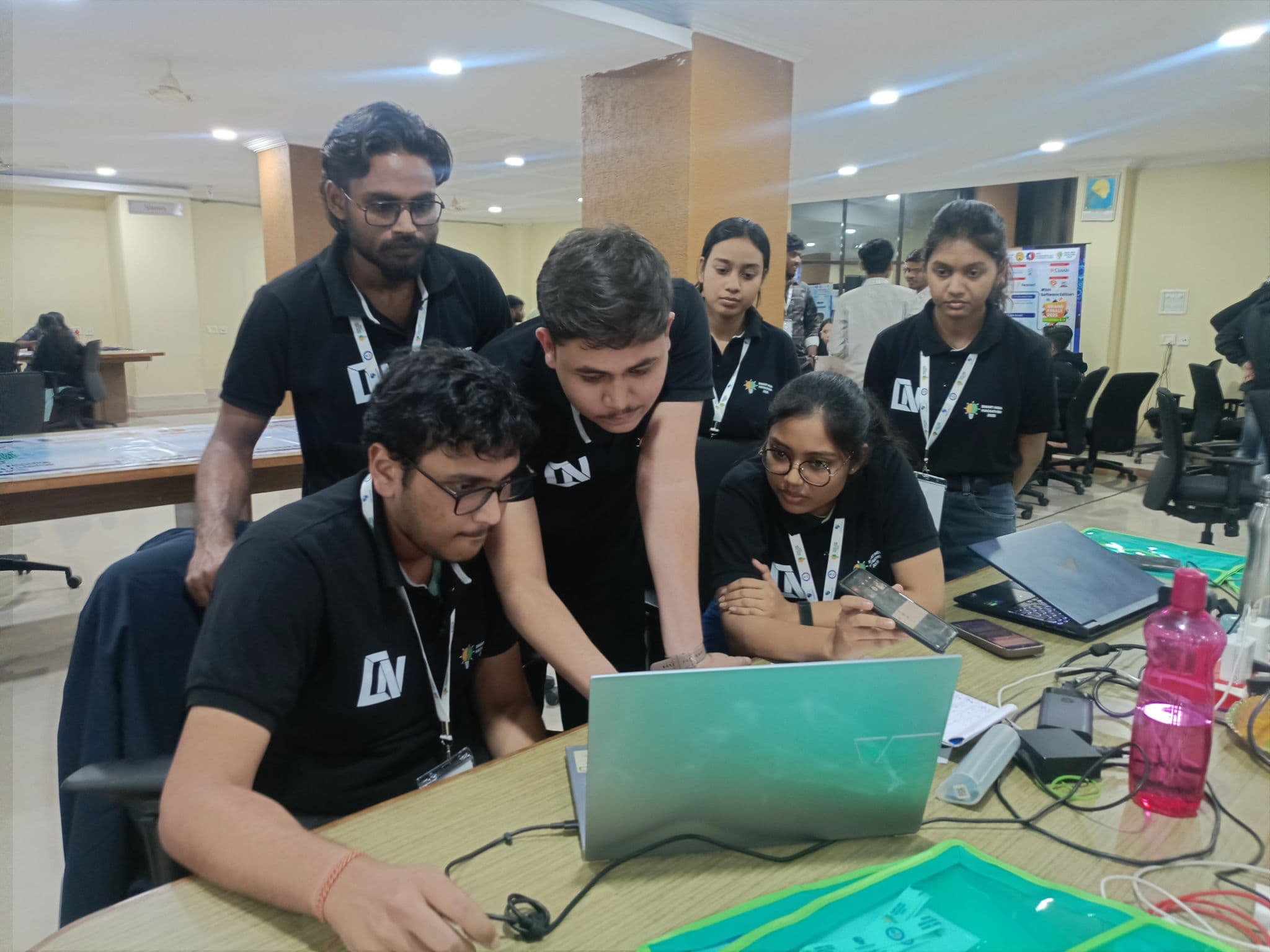 Team members collaborating around a laptop during a hackathon