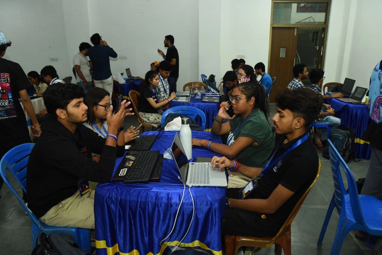 Hackathon participants collaborating across blue tables