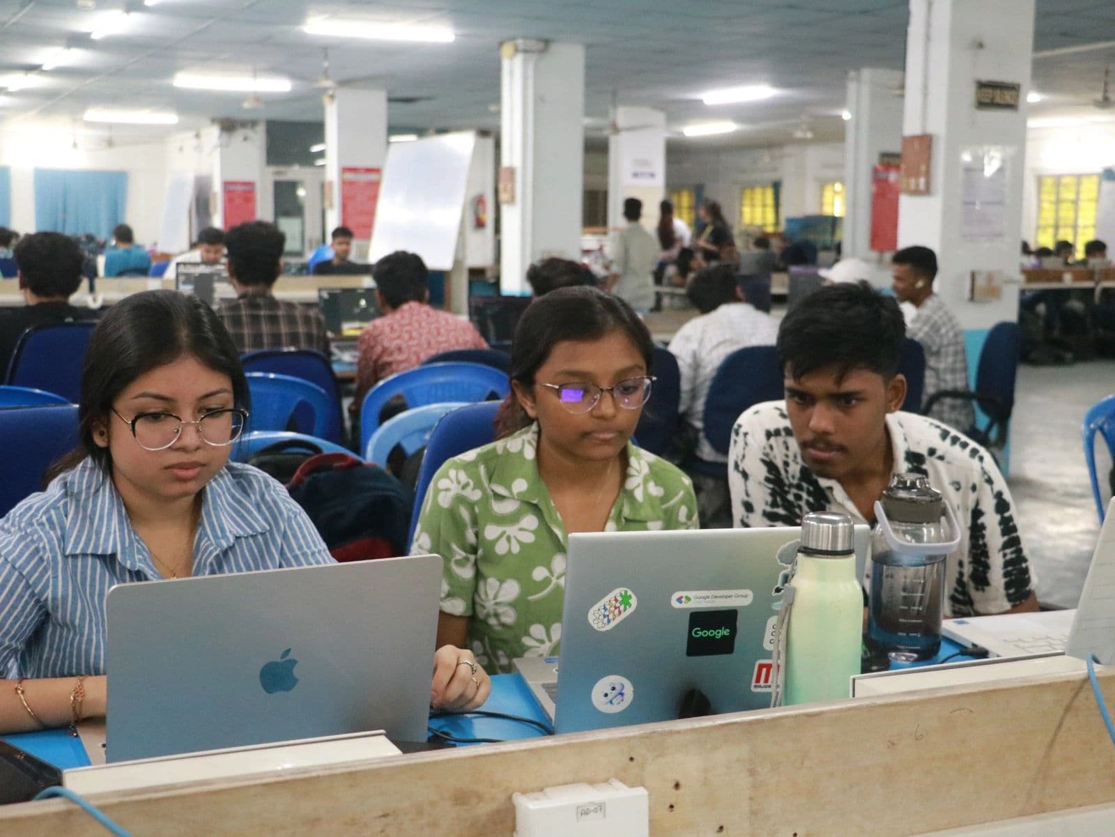 Focused participants working on laptops at a hackathon